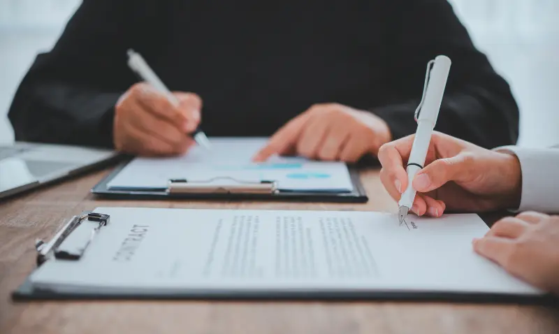People signing a document on clipboards during an in-person notarization.