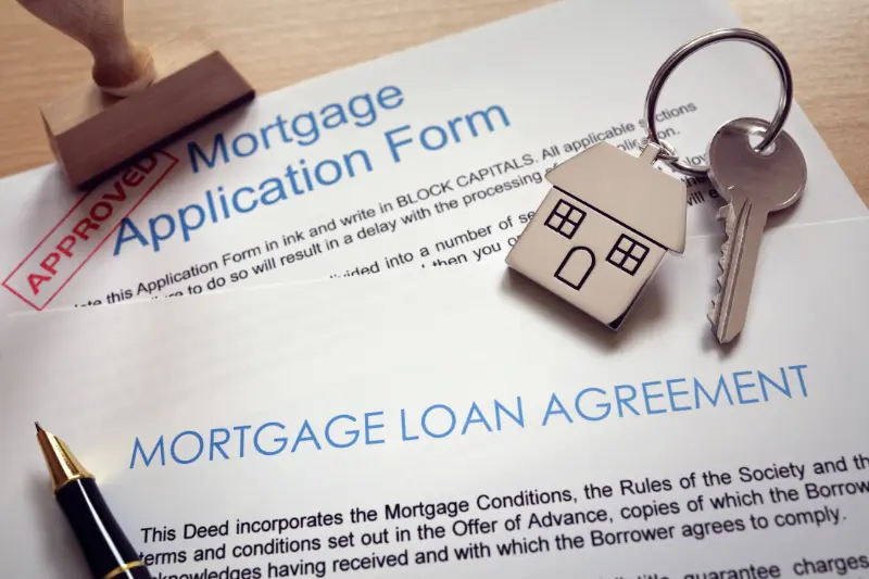 Mortgage application and loan agreement with house key and approved stamp.